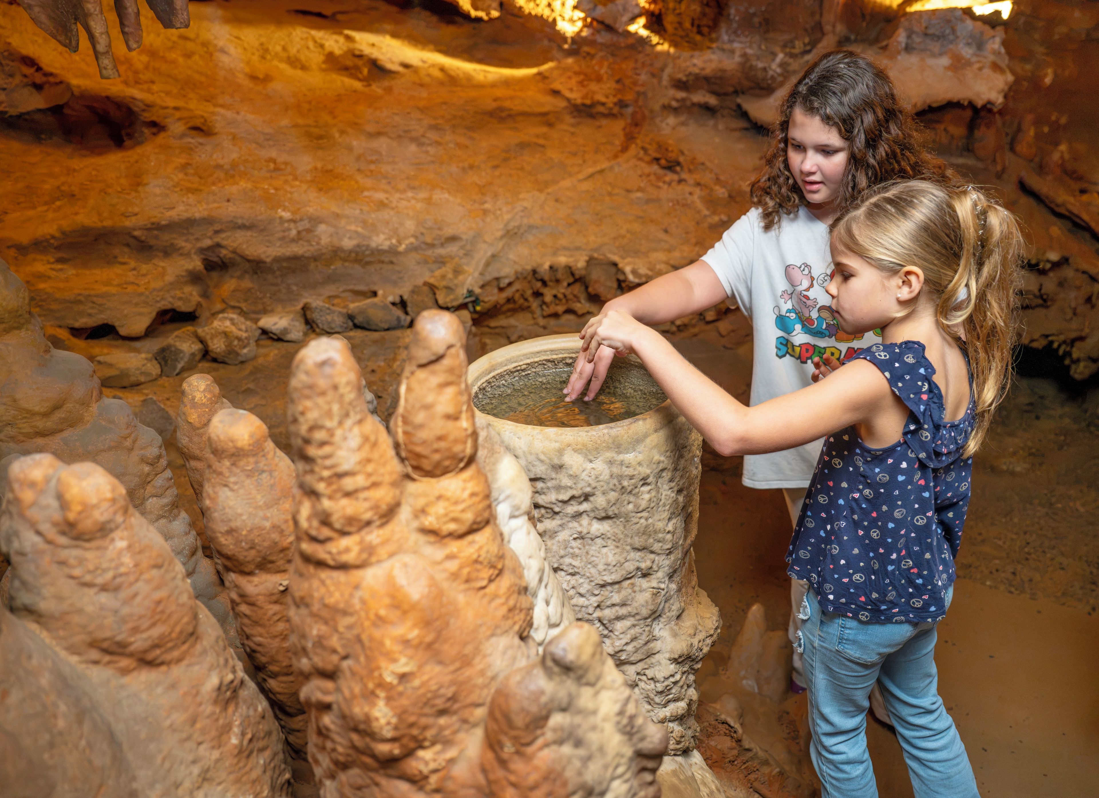 A person interacting with a large, textured stone structure in a cave-like environment.