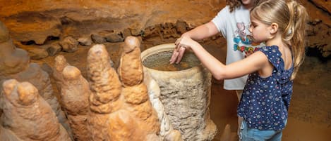 A person interacting with a large, textured stone structure in a cave-like environment.