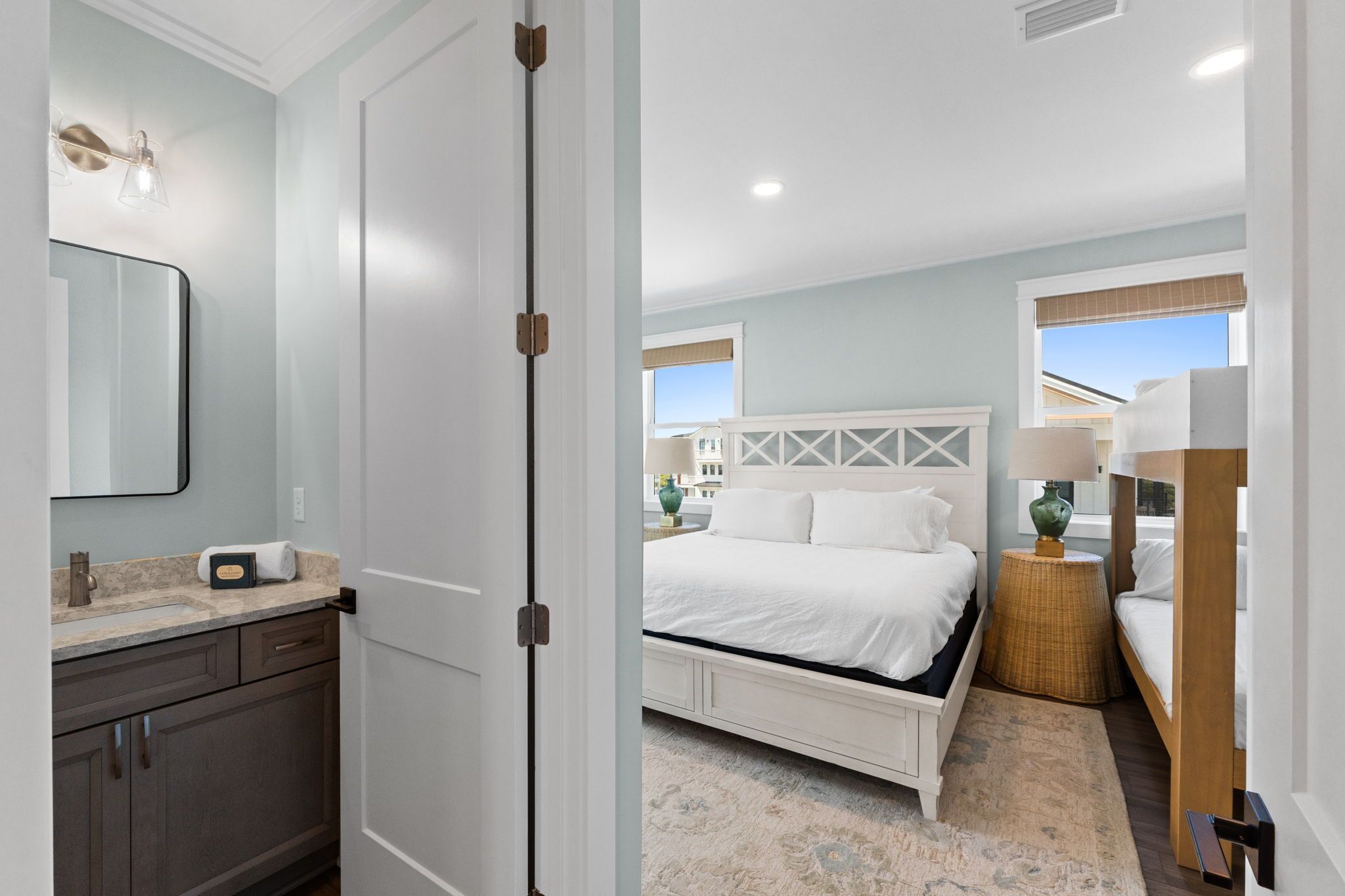 A bedroom with a bed, a nightstand, a lamp, and a view of the outside.
