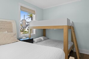 A bunk bed with a wooden frame and white bedding, a bedside table with a lamp, and a window with a view of palm trees. - Gulfstone: Gulf Front New Build, Private Pool, Pet Friendly, Sugar Sands Communi (Mexico Beach)