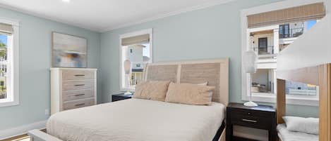 Une chambre à coucher avec un lit, des tables de chevet, une commode et une fenêtre.
