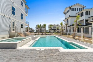 A residential area with a swimming pool, paved walkways, and multiple houses with balconies. - Gulfstone: Gulf Front New Build, Private Pool, Pet Friendly, Sugar Sands Communi (Mexico Beach)