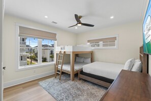 A bedroom with bunk beds, a ceiling fan, a window with blinds, and a view of neighboring houses. - New Build, Private Pool, Pet Friendly, Sugar Sands Community (Mexico Beach)