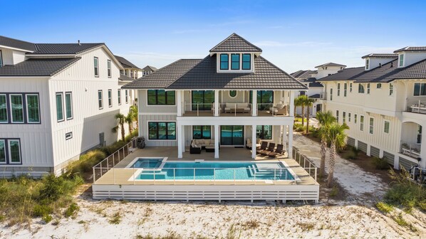 Ein zweigeschossiges Haus mit Pool, überdachter Terrasse und Blick auf den Strand.