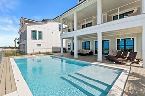 Ein modernes Hotel mit einem großen Außenpool, einer überdachten Terrasse zum Sitzen und Blick aufs Meer.