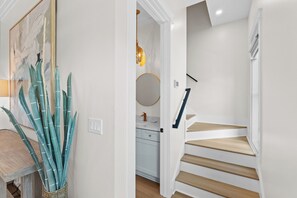 A staircase with wooden steps and white walls, leading to a room with a kitchen area. - New Build, Private Pool, Pet Friendly, Sugar Sands Community (Mexico Beach)