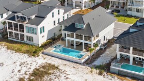 Ein Anwesen direkt am Strand mit mehreren Häusern, einem Swimmingpool und einer überdachten Terrasse.
