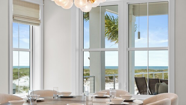 Ein Essbereich mit einem großen Tisch, gedeckt für vier Personen, mit Blick auf einen Strand.