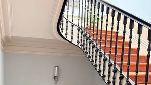 Eine Treppe mit schwarzen Balustraden und Holzstufen, einer Wandleuchte und zwei Blumentöpfen.