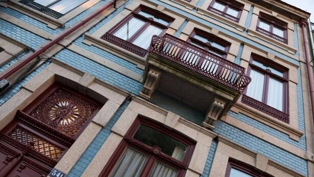 Ein mehrstöckiges Gebäude mit einem Balkon im zweiten Stock.