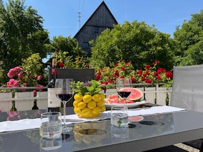 A table with a bottle of wine, glasses, lemons, and a watermelon.