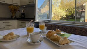 A breakfast table with pastries, a cup, and glasses of orange juice, a vase with flowers, and a bottle on the counter. - Apartment Sieglinde with Private Terrace in Bad Dürrheim Öfingen (Bad Dürrheim)