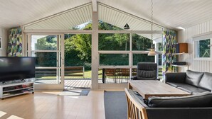 Een ruime woonkamer met een grote televisie, een bank en een eethoek met een tafel en stoelen.