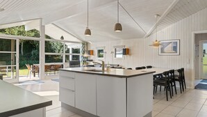 Een ruime keuken met een groot eiland, witte kasten en hanglampen.