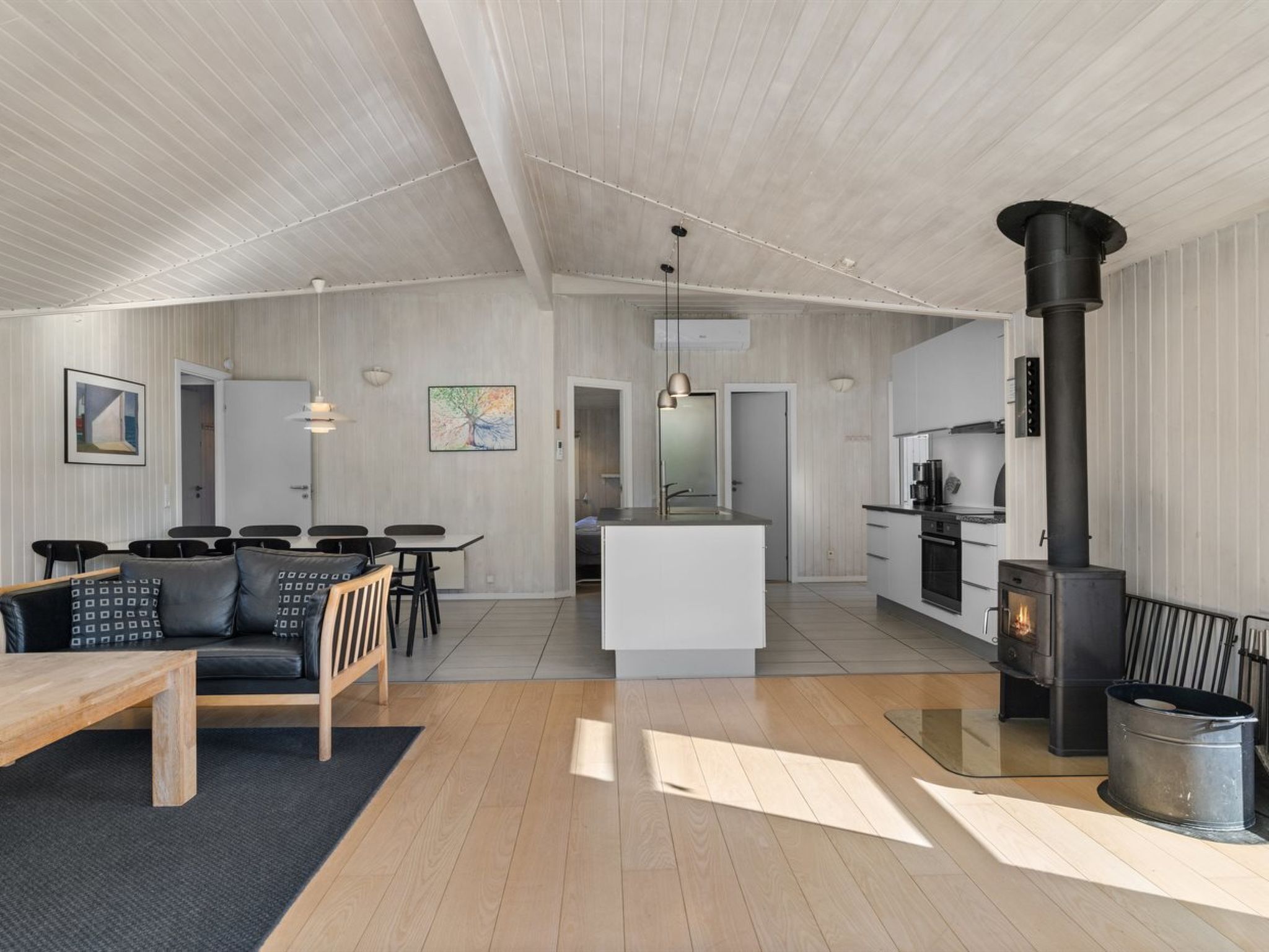 Een moderne woonruimte met een eethoek, keuken en een houtkachel.