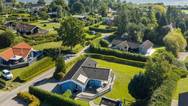 Een kustgebied met woonhuizen, groene gazons en uitzicht op zee.