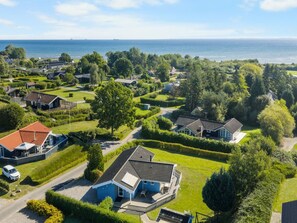 Un quartier résidentiel situé sur la côte, avec des maisons, de pelouses verdoyantes et une vue sur la mer.