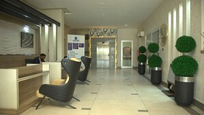 A hotel reception area with a reception desk, seating area, and a signboard for hotel services. - 2020 Apartment Guzape (Abuja)