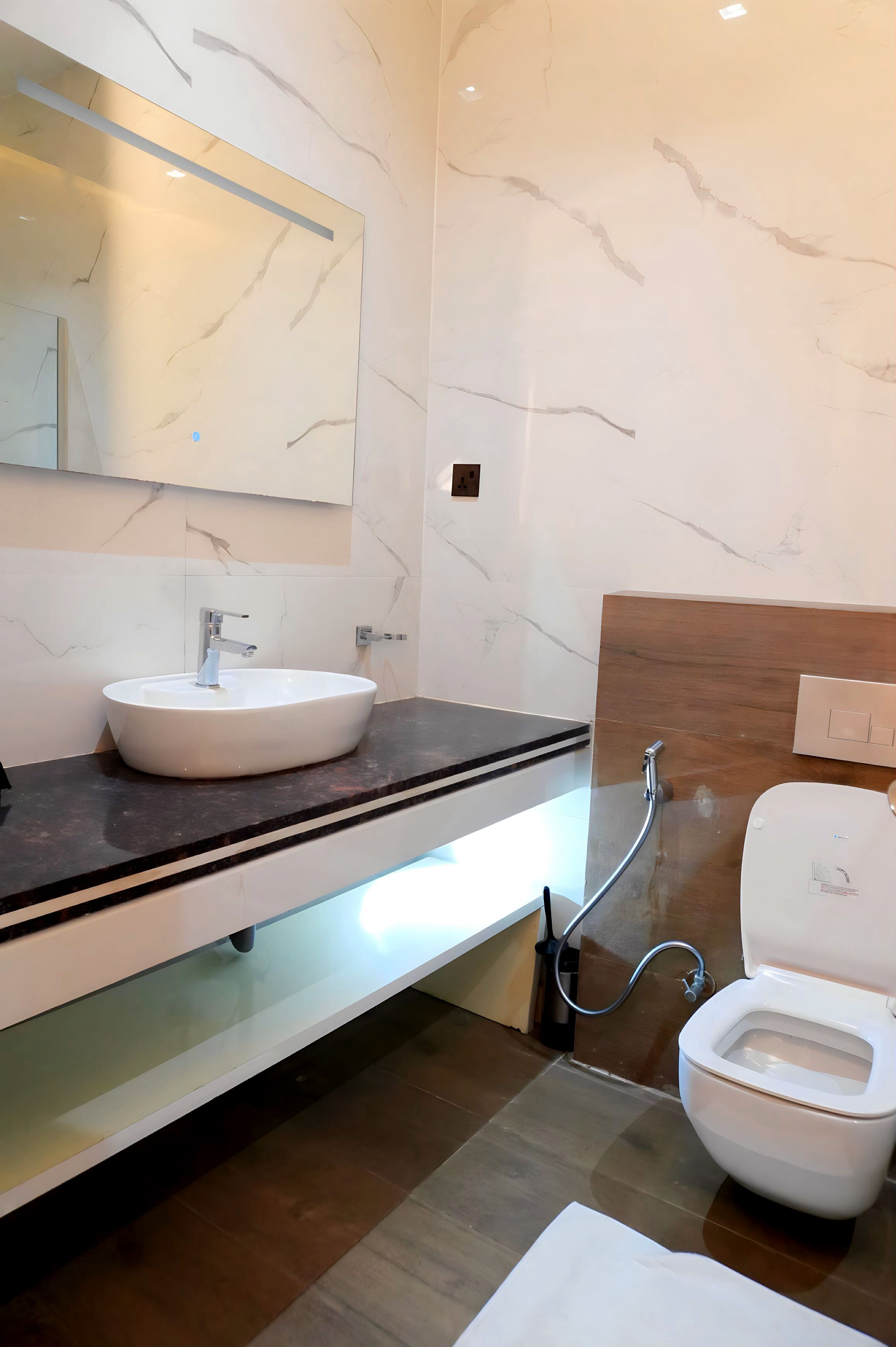 A modern bathroom with a marble sink, a mirror, and a toilet.