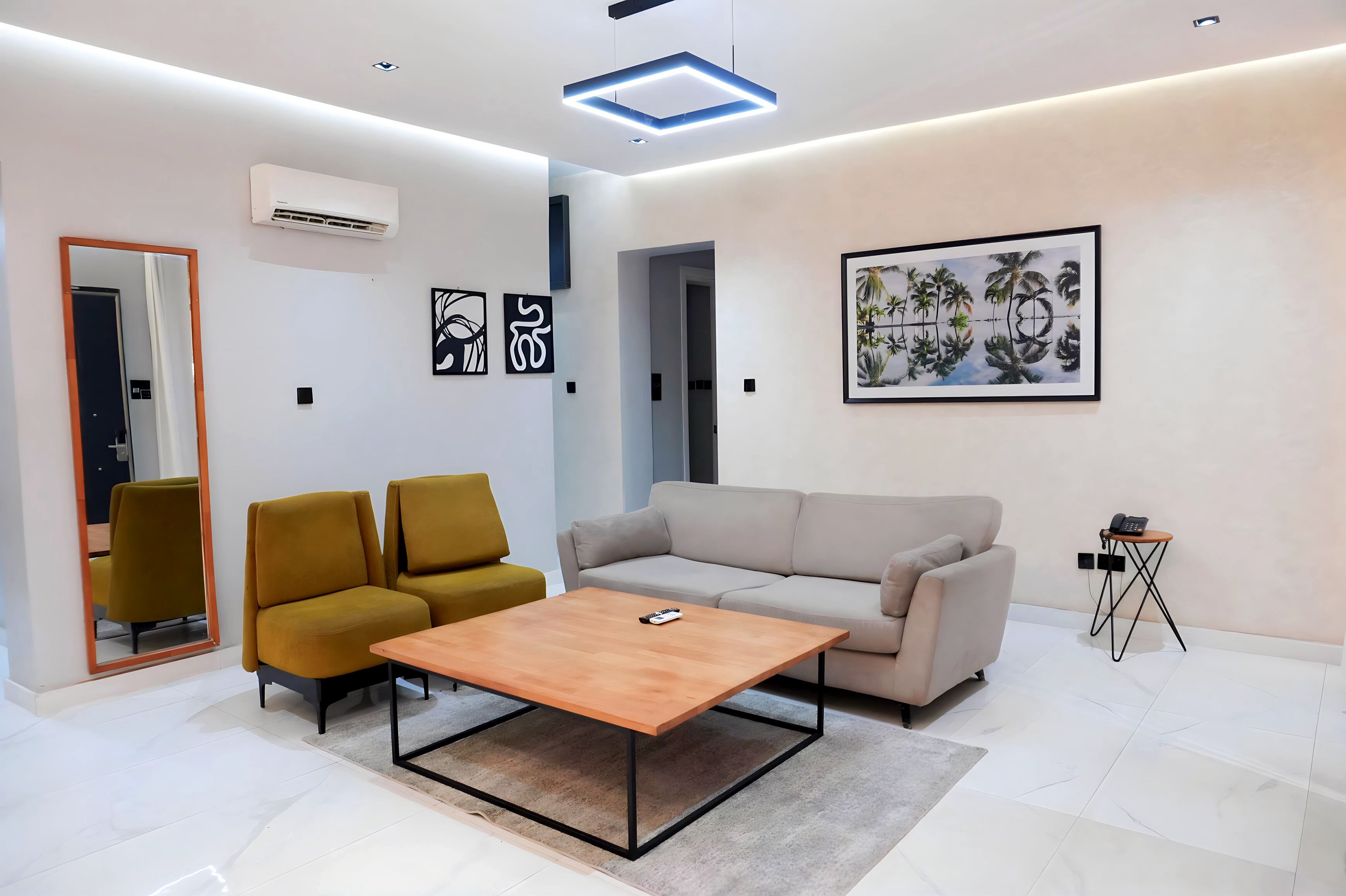 A modern living room with a sofa, two armchairs, a coffee table, and a side table with a phone.