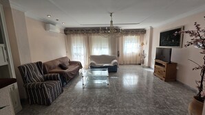 Ein geräumiges Wohnzimmer mit einer Couch, einem Sessel und einem Glastisch.