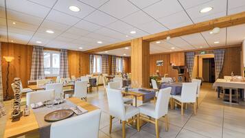 A spacious dining area with multiple tables and chairs, wooden paneling, and a clean, modern design.