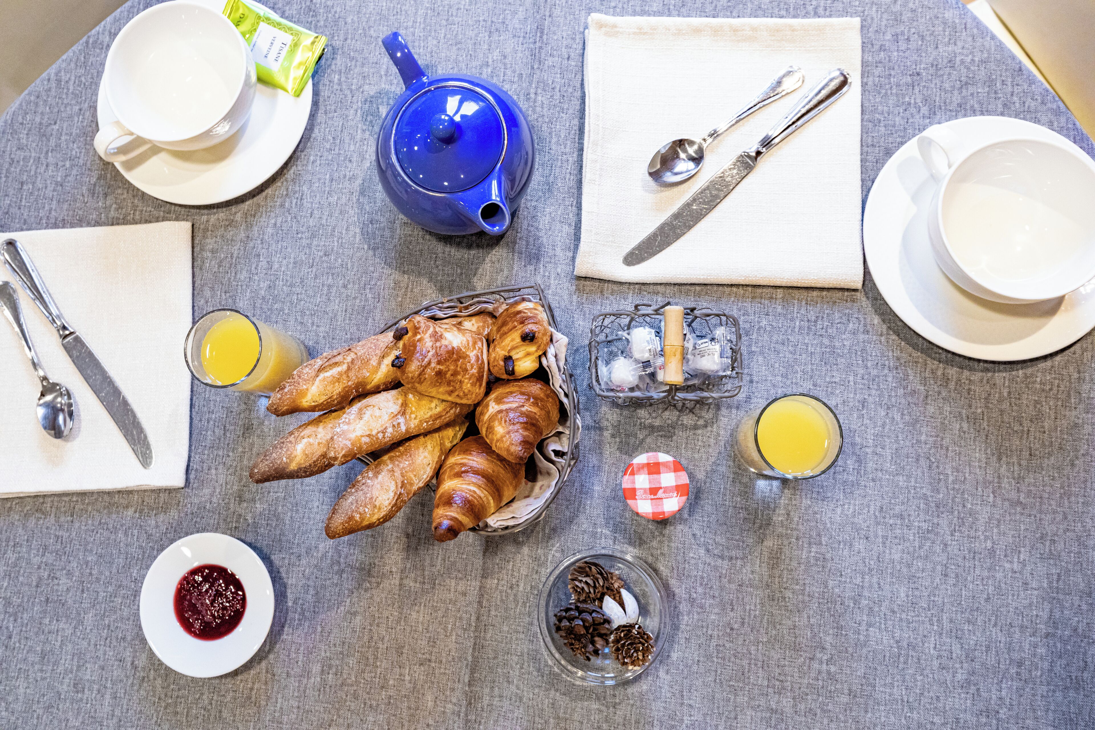 Uma mesa de café da manhã com croissants, suco e um bule de chá.