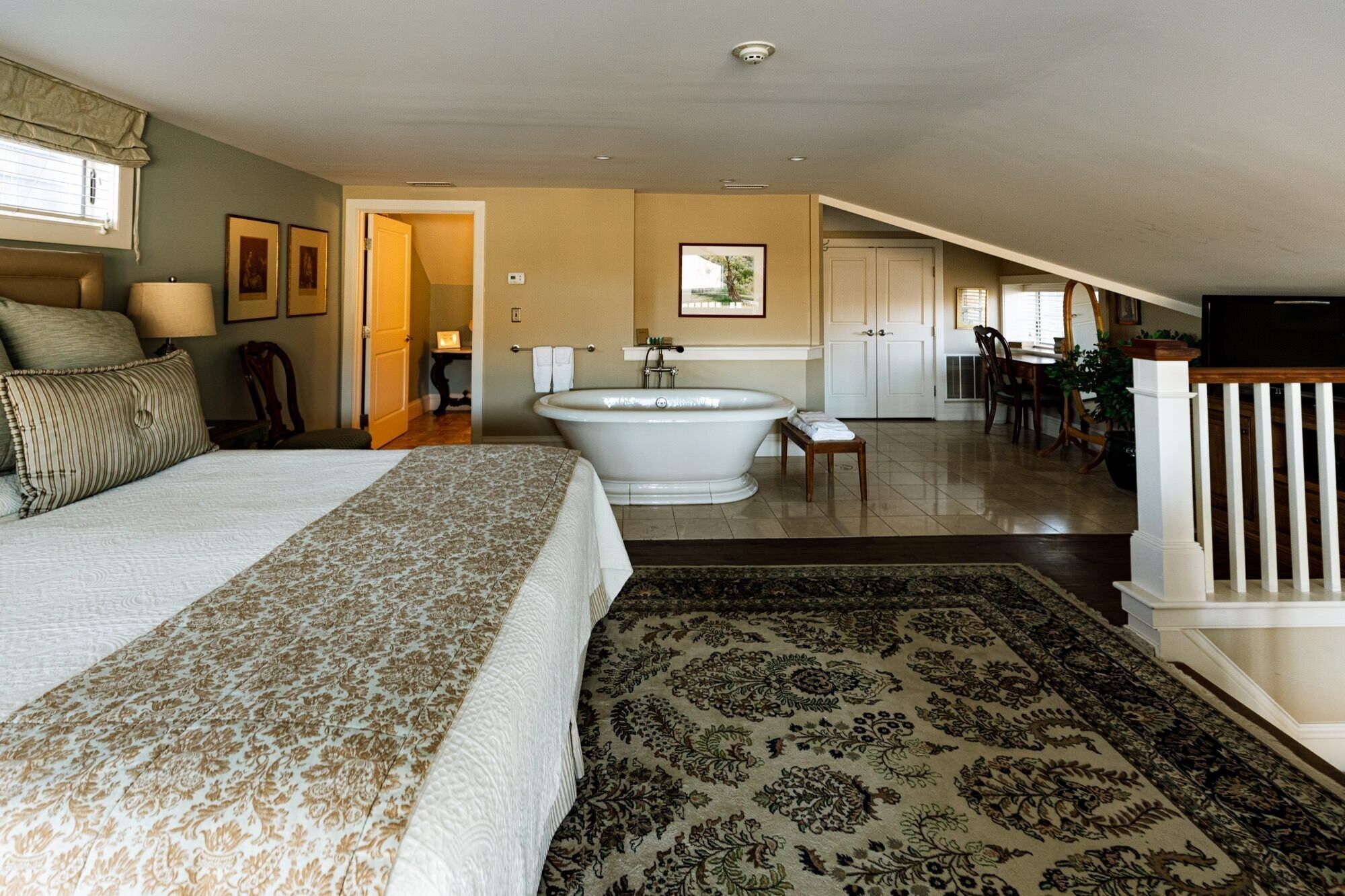 A spacious bedroom with a large bed, a bathtub, and a dining area with a view.