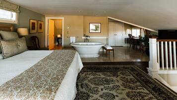 A spacious bedroom with a large bed, a bathtub, and a dining area with a view.