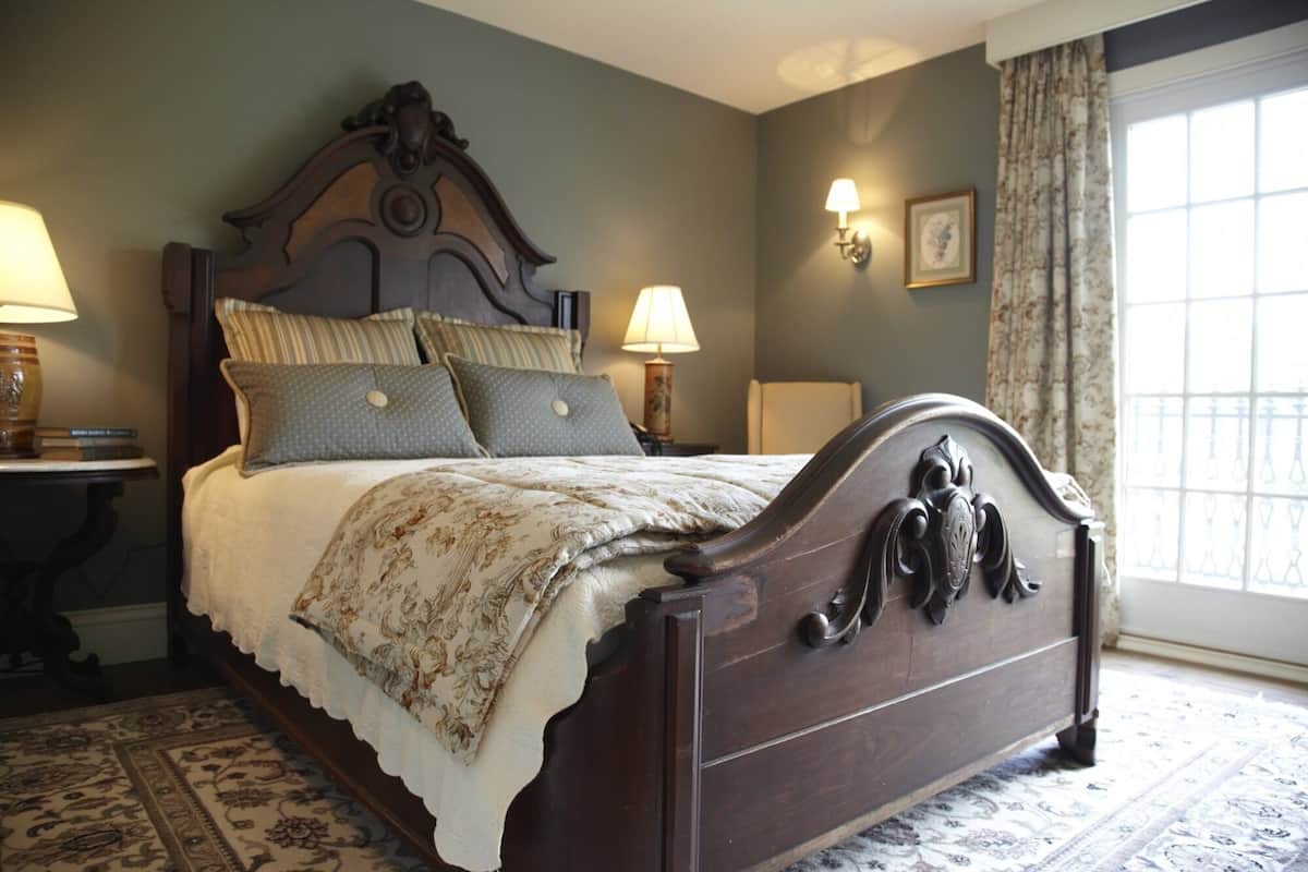 A classic wooden bed with a decorative headboard, multiple pillows, and a patterned bedspread.
