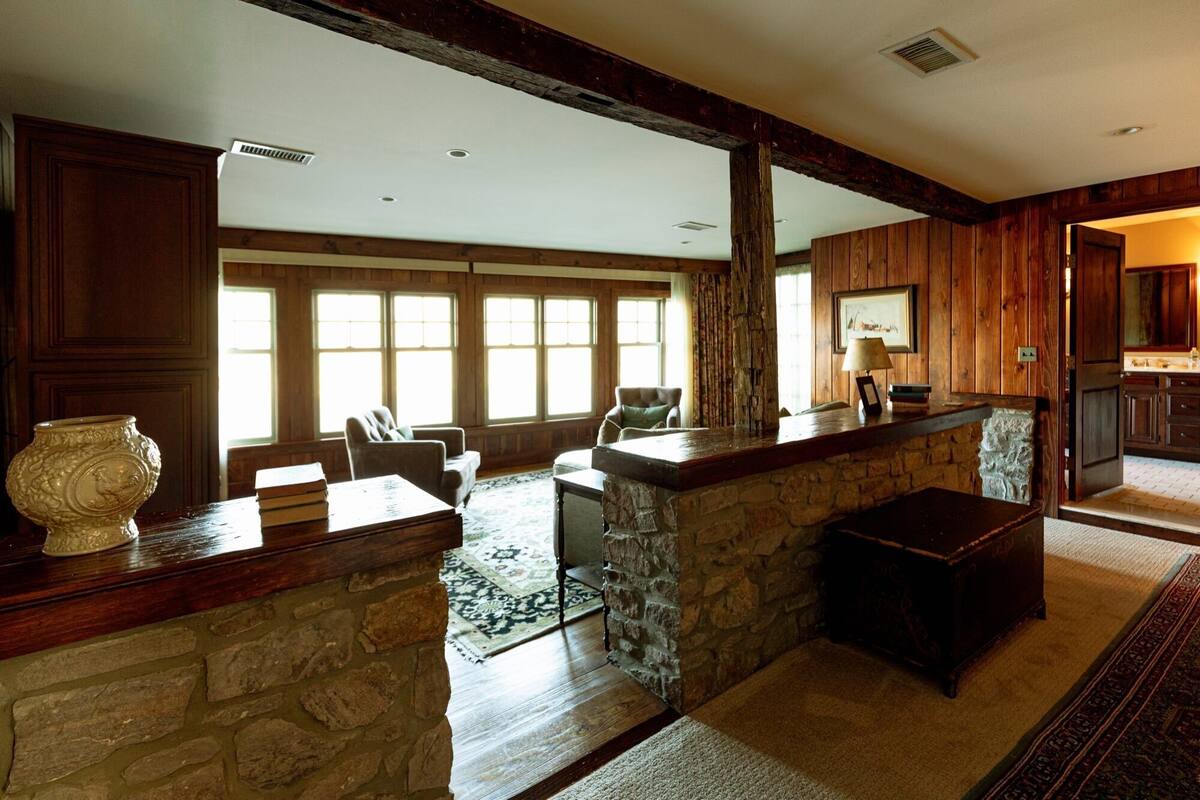 A spacious lobby with a stone fireplace, wooden paneling, and large windows allowing natural light.