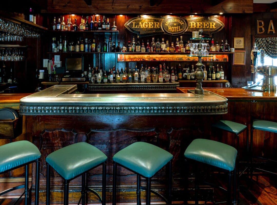 Un espace bar avec un comptoir, des tabourets et une variété de bouteilles d’alcool.
