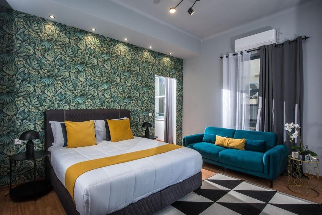 Ein Schlafzimmer mit einem großen Bett, einem Türkis-farbenen Sofa und rahmigem Wandpapier.