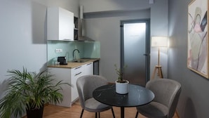 Cocina compacta con lavabo, armarios y un pequeño comedor con dos sillas y una mesa.