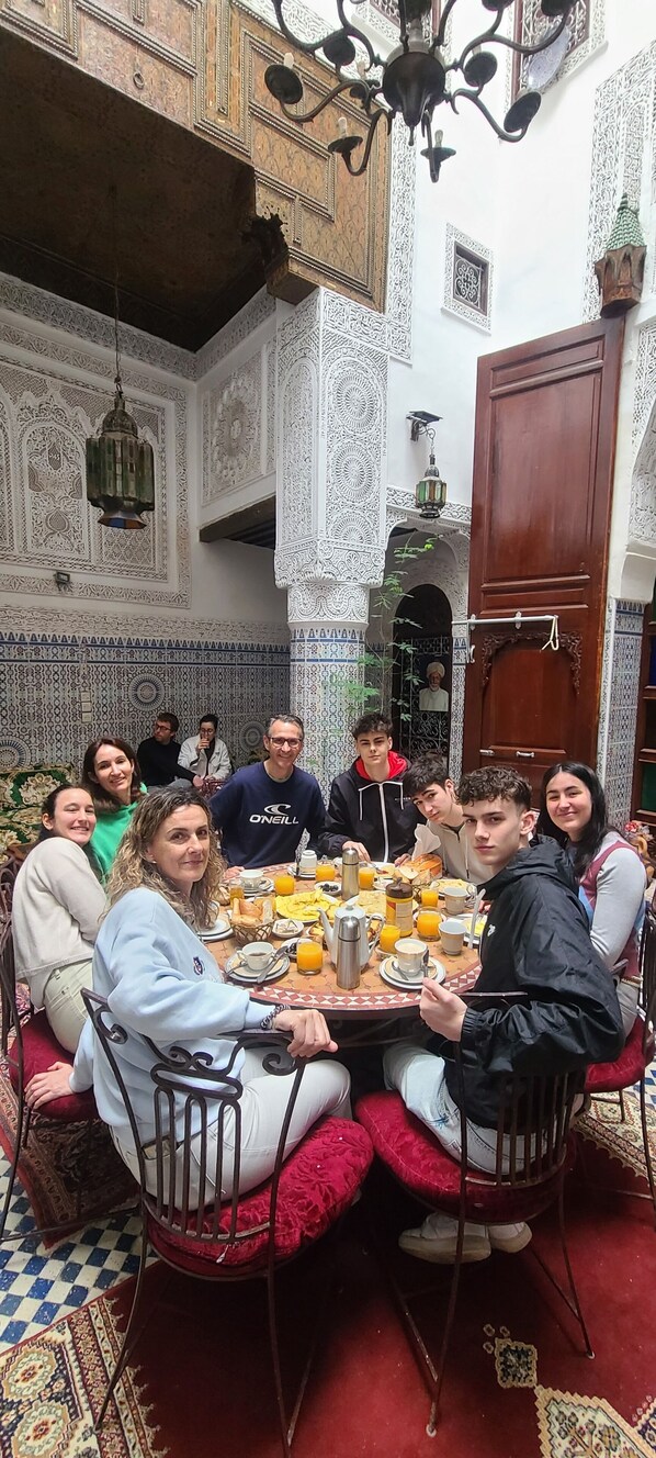 A group of people dining in a room with intricate tile work and a wooden door. - Riad Lala Kenza (Fes)