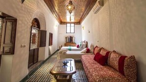 A narrow hallway with a checkered floor, a sofa with red cushions, and a patterned ceiling. - Riad Lala Kenza (Fes)