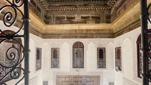 An ornate interior with intricate wall designs, a central chandelier, and a patterned ceiling. - Riad Lala Kenza (Fes)
