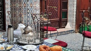 A traditional Moroccan dining setup with a checkered tablecloth, a variety of dishes, and a drink. - Riad Lala Kenza (Fes)