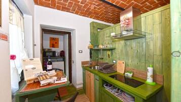 A compact kitchen with green cabinetry, a brick ceiling, and a small dining area with a table and chairs.