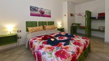 A bedroom with a floral bedspread, green headboard, bedside tables with lamps, and a bunk bed with storage.