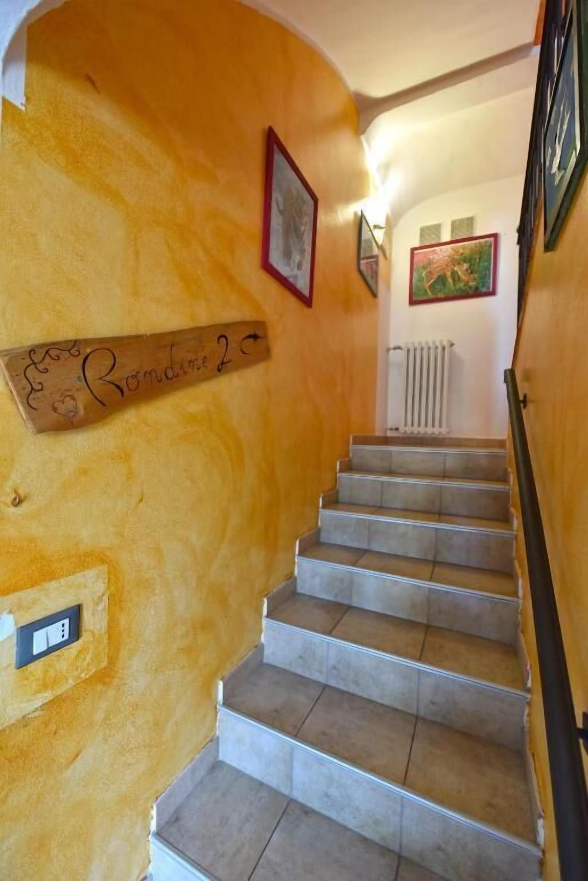 Una escalera con barandilla de madera y un cartel en la pared.