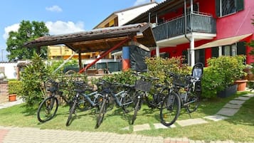 Een rood gebouw met een balkon, een overdekt terras en fietsen voor de gevel.