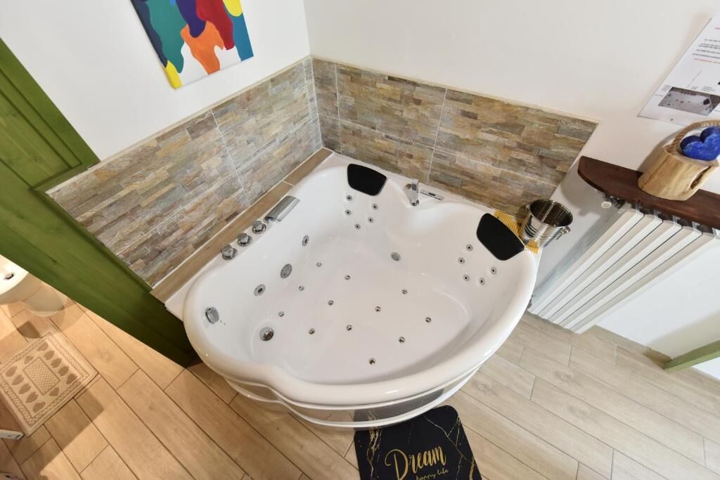 Un baño moderno con una bañera independiente, un banco de madera y una pared con azulejos de piedra.