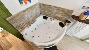 Un baño moderno con una bañera independiente, un banco de madera y una pared con azulejos de piedra.