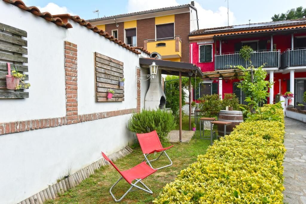 A courtyard with a white building, a red chair, and a yellow flower bed.