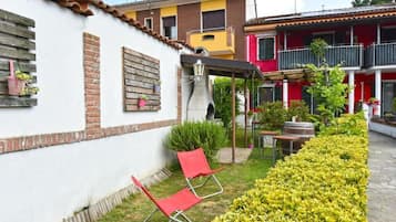 A courtyard with a white building, a red chair, and a yellow flower bed.
