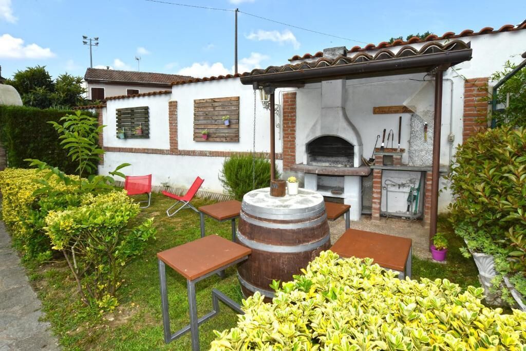 Een terras met een bakoven, zitplaatsen buiten en een tuin.