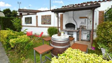 Een terras met een bakoven, zitplaatsen buiten en een tuin.