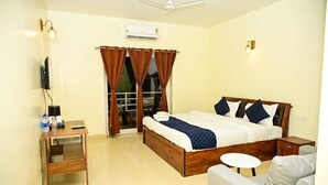 Habitación de hotel con cama, escritorio, silla, televisor y aire acondicionado.