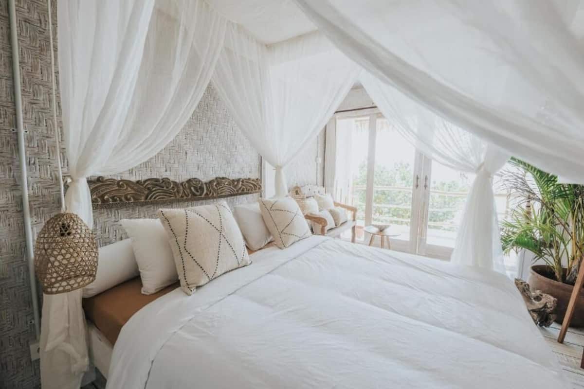 A spacious bedroom with a large bed, white bedding, and a canopy.
